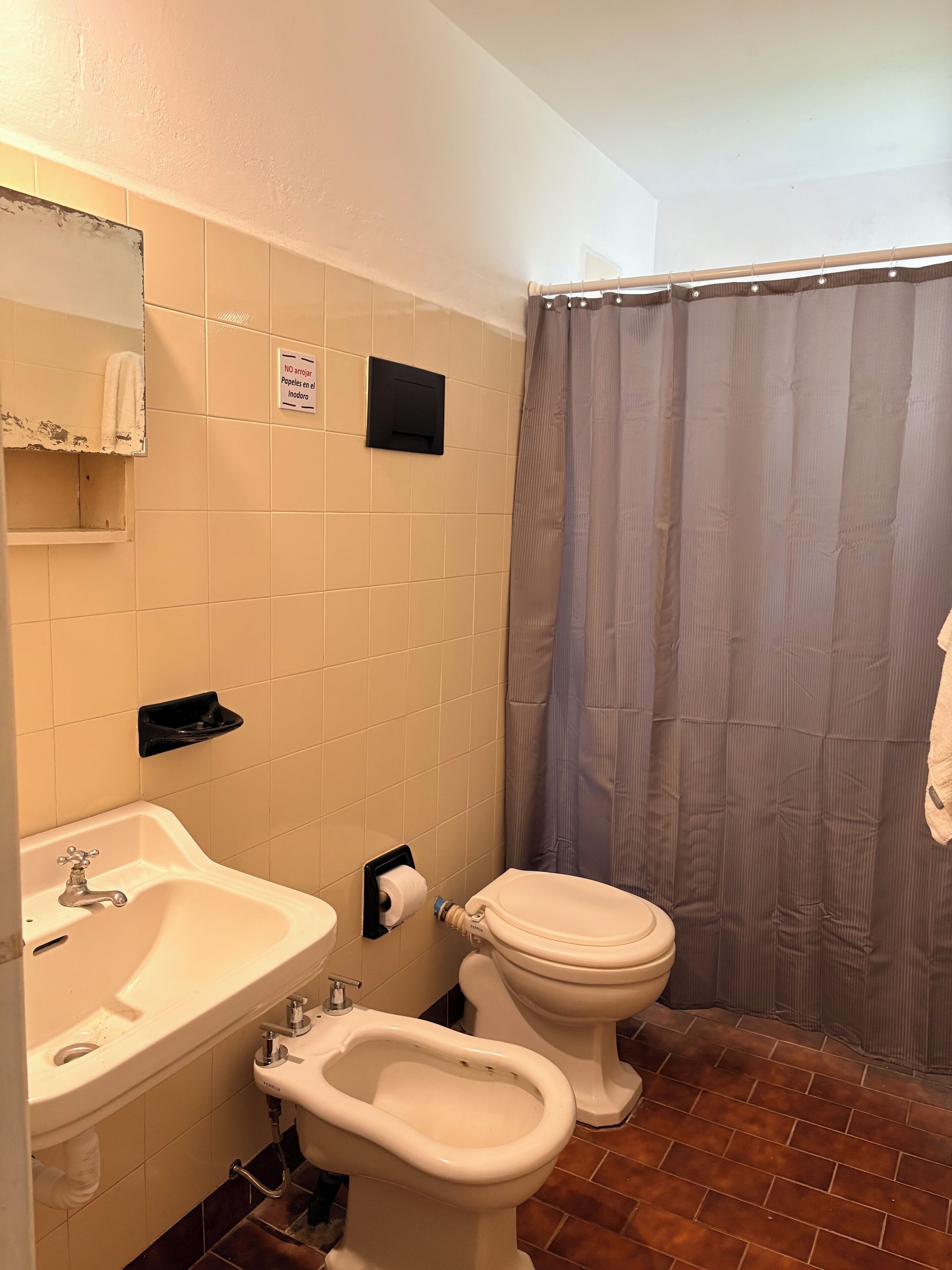Un baño con lavamanos, bidé, inodoro y cortina de ducha.