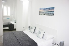 A modern bedroom with a bed, bedside tables, a nightstand, and a painting of a beach scene. - Cottage the Butterfly - Cozy Apartment Just Minutes from the Ocean (Manduria)