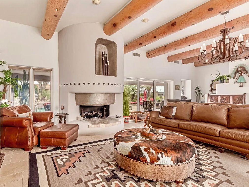 Un salón amplio con chimenea, muebles de cuero y techo rústico.