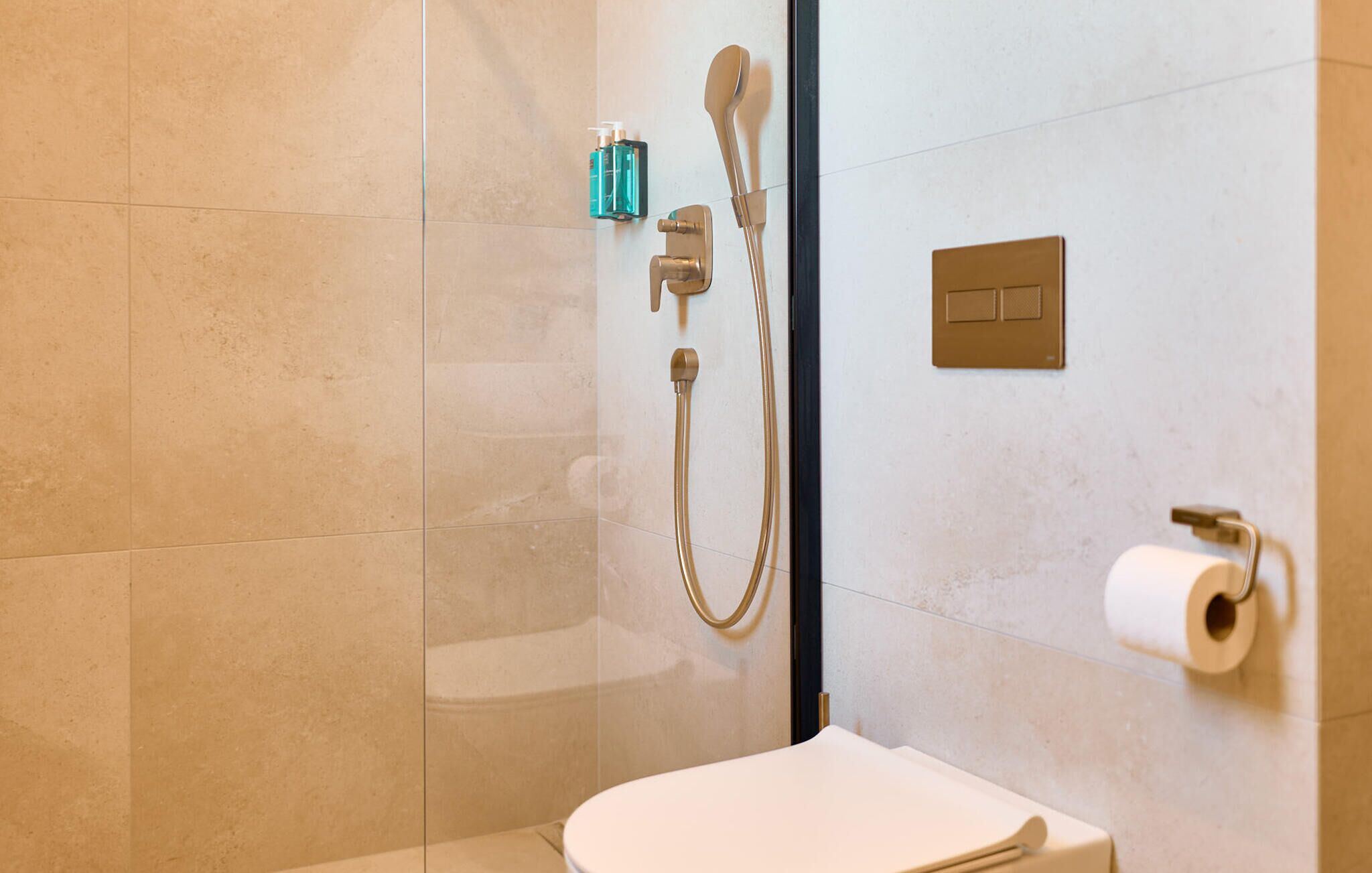 Une salle de bain comprenant des toilettes, une douche avec un pommeau de douche amovible et un porte-serviettes.
