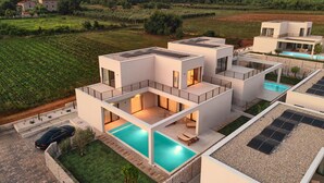Una casa moderna de varios pisos con piscina, paneles solares y vistas al campo circundante.