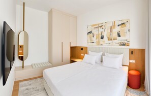 Una habitación de hotel moderna con una cama grande, un televisor de pantalla plana, cabecero de madera y arte abstracto en la pared.