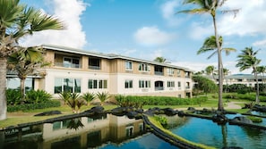 Ein Hotel mit Schwimmbad, Palmen und einem gepflegten Garten.