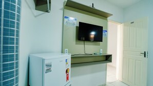Habitación de hotel con un televisor montado en la pared, un refrigerador pequeño y una puerta con el número 202.