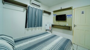 Un dormitorio con una cama, aire acondicionado, televisor y una puerta.