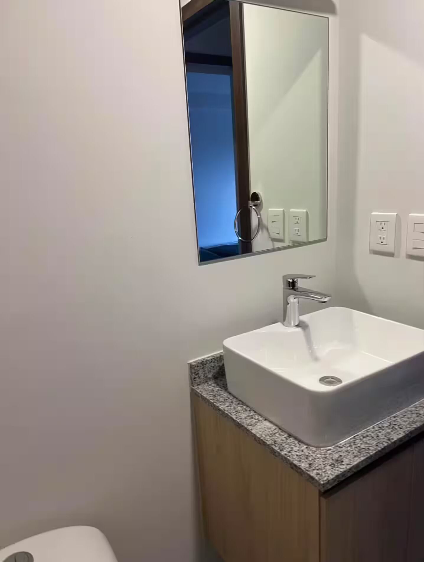 A bathroom with a white sink, a mirror, and a granite countertop.