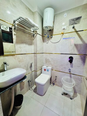 A bathroom with a white sink, toilet, and shower. - Hotel Classic Crowne (New Delhi)