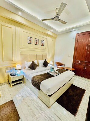 A hotel room with a bed, bedside table, lamp, and a wardrobe. - Hotel Classic Crowne (New Delhi)