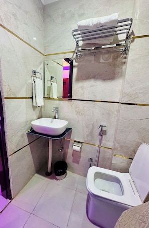 A compact bathroom with a white sink, a toilet, and a mirror. - Hotel Classic Crowne (New Delhi)