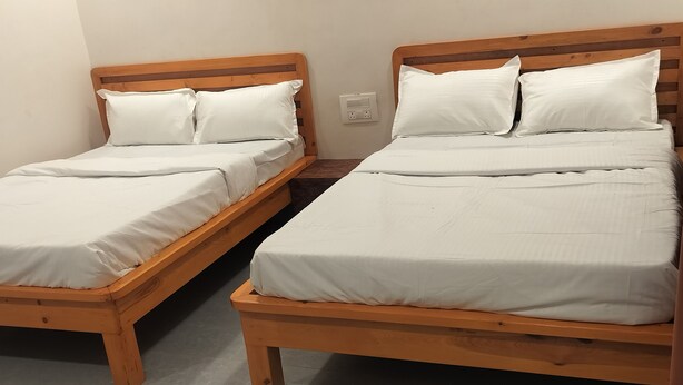 Two wooden beds with white bedding in a room with a tiled floor.