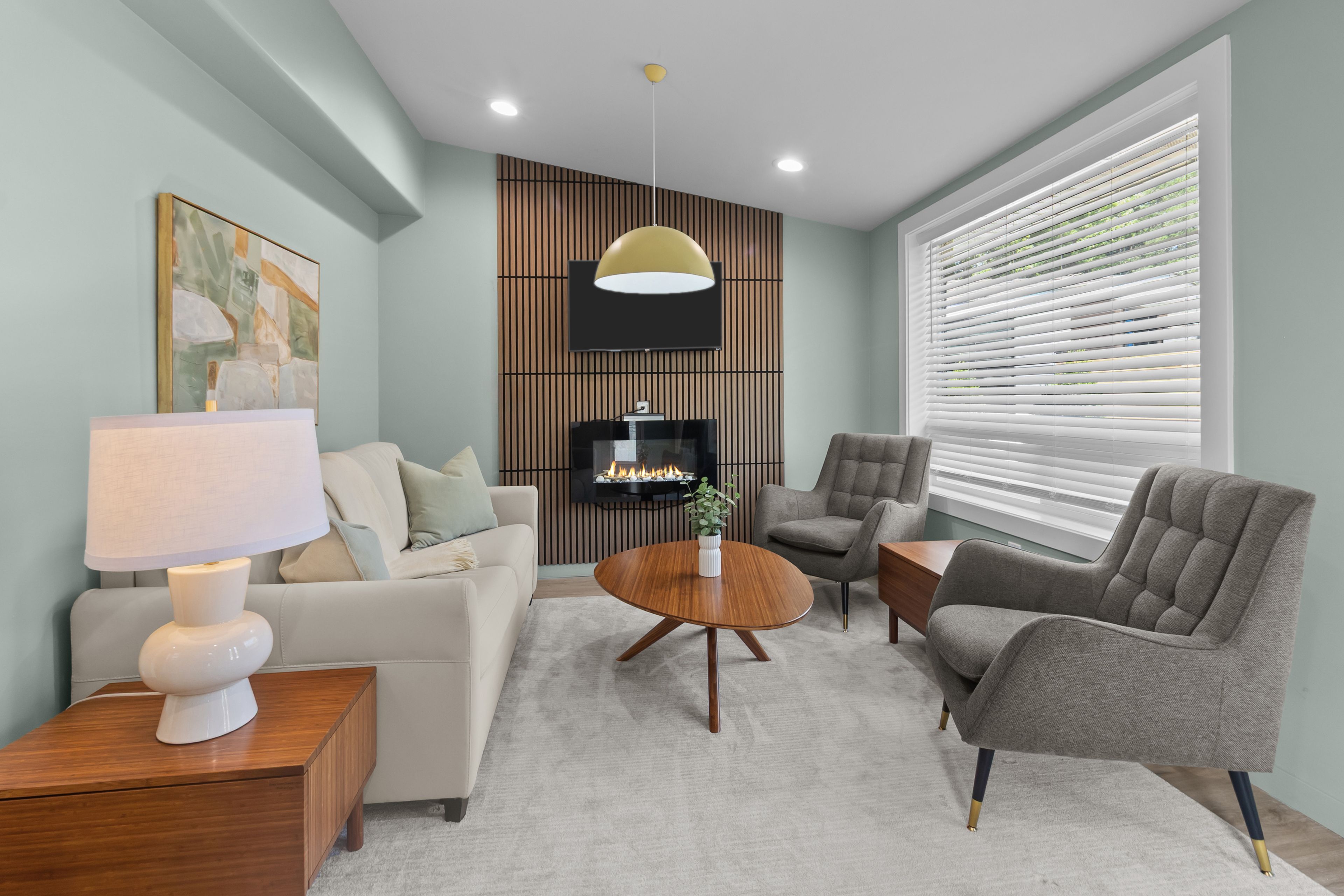 A modern living room with a sofa, armchairs, a coffee table, and a TV.