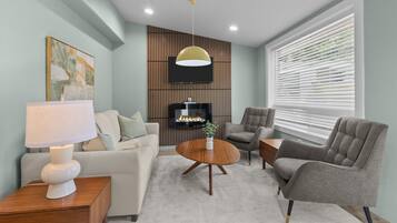 A modern living room with a sofa, armchairs, a coffee table, and a TV.