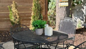 A round metal table with a potted plant and two salt shakers.