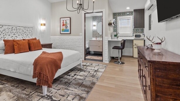 A modern bedroom with a large bed, a desk, and a television.