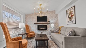A living room with a fireplace, two armchairs, a sofa, and a coffee table. - Unit 5. Parent Trap Suite The American Hotel. Dwtn Williams Bay. Steps to beach. (Williams Bay)