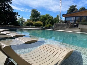Une piscine avec des chaises longues et un mur en pierre.