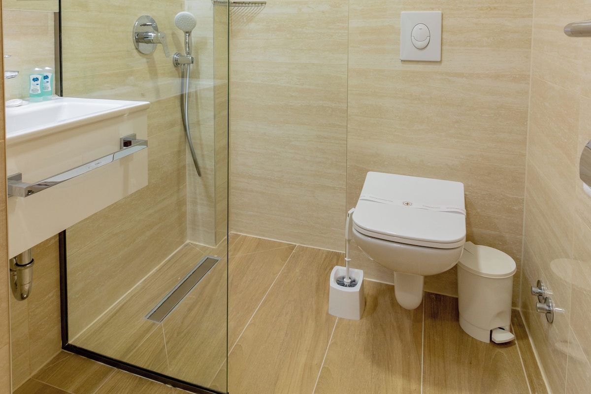 Un baño moderno con ducha de vidrio, inodoro y lavamanos.