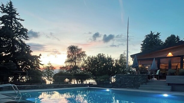 En swimmingpool med liggestole og en bygning i baggrunden.