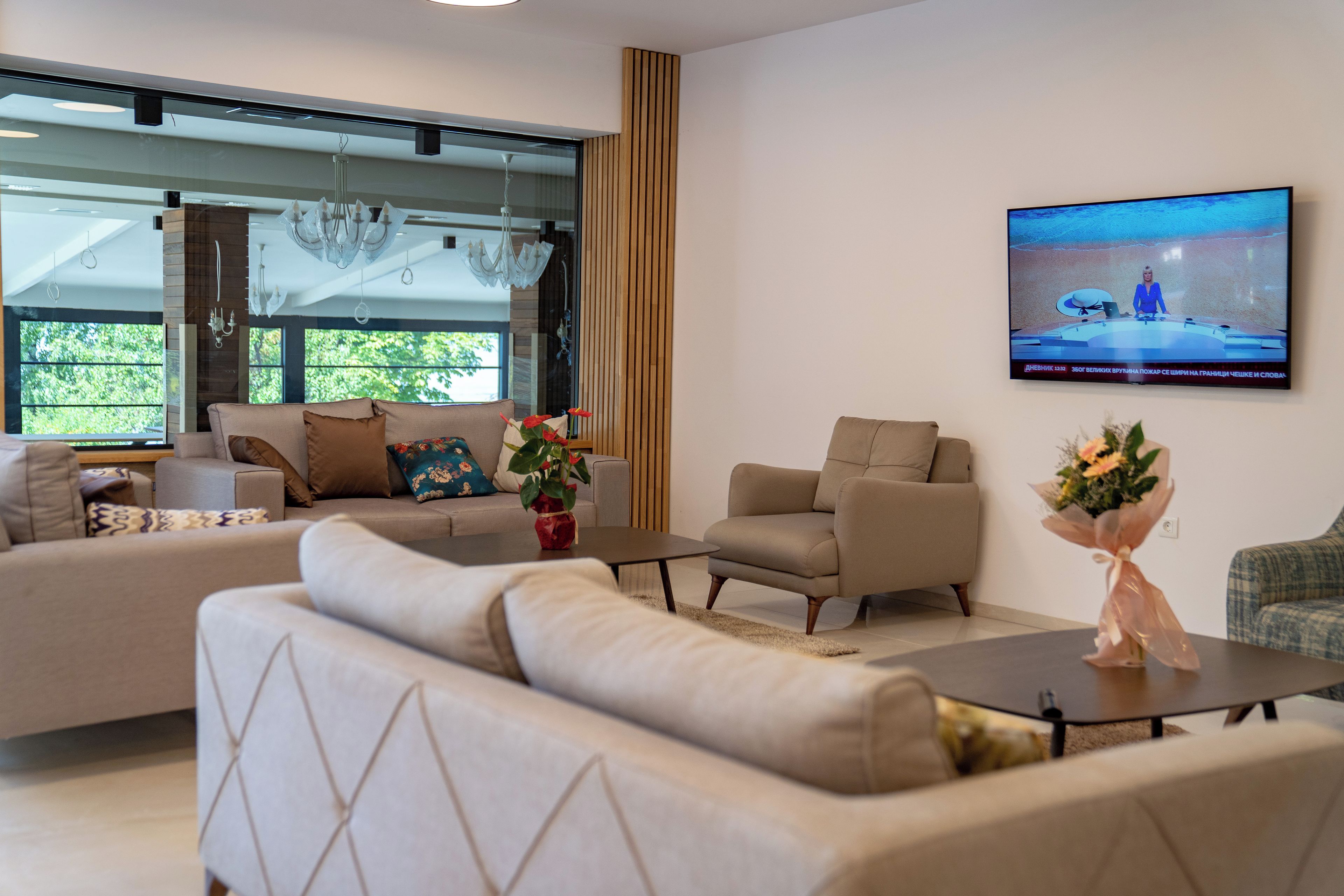 Una sala de estar moderna con un televisor grande, asientos cómodos y vistas a través de un ventanal.