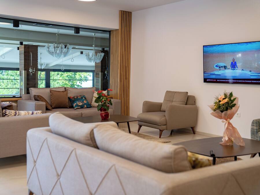 A modern living room with a large TV, comfortable seating, and a view through a glass door.