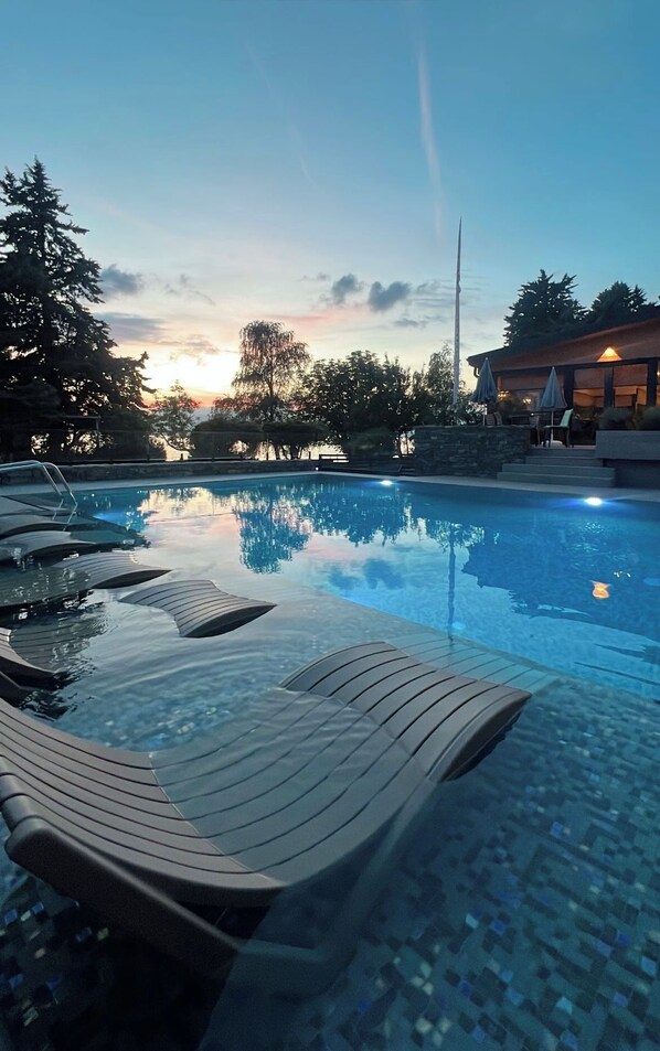 Une piscine avec des chaises longues et un bâtiment en arrière-plan.