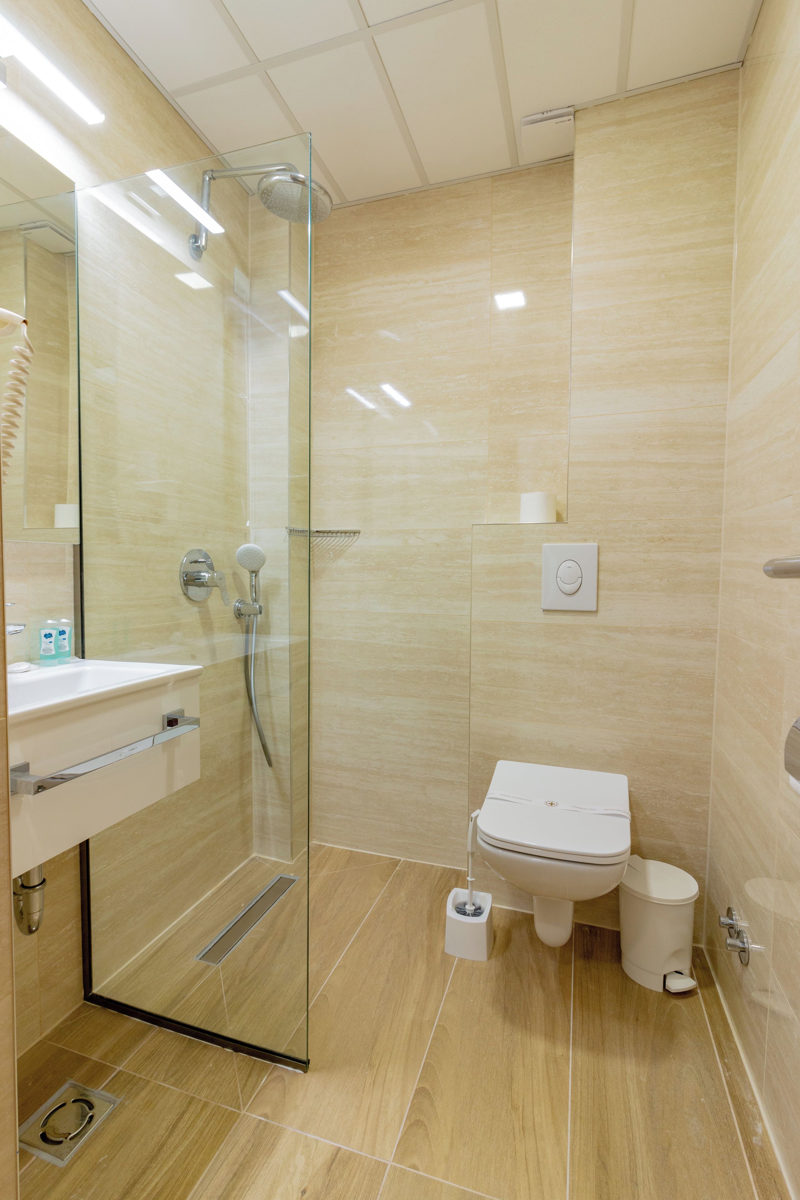 Een moderne badkamer met een glazen douchecabine, toilet en wastafel.