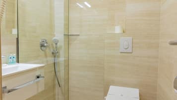 Een moderne badkamer met een glazen douchecabine, toilet en wastafel.