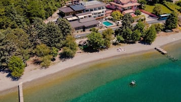 Luchtbeeld van een kustbezit met een groot huis, een zwembad en een strand.