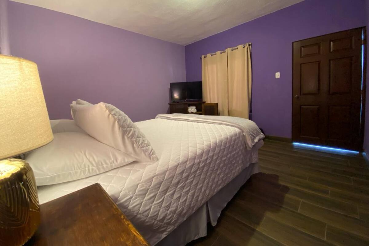 Ein Schlafzimmer mit Bett, Fernseher, Lampe und einer Tür.
