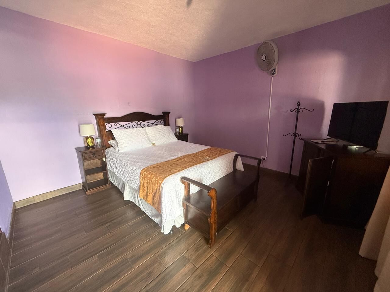 A bedroom with a bed, bedside tables, a desk, and a chair.