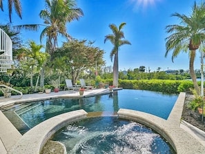 A swimming pool with a hot tub, surrounded by palm trees and lounge chairs. - Angler's Luxury Waterfront in Bokeelia - Infinity Pool, Bar & Dock for Fishing (Bokeelia)