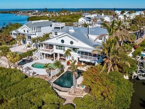 A large, modern house with multiple levels, a swimming pool, and a view of the ocean. - Angler's Luxury Waterfront in Bokeelia - Infinity Pool, Bar & Dock for Fishing (Bokeelia)