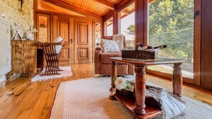 Une pièce chaleureuse avec un plancher en bois, une grande fenêtre, une table en bois et un coin salon confortable.