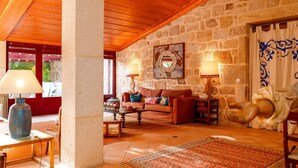 Una habitación con paredes de piedra y techo de madera, un sofá, una mesa y una alfombra estampada.