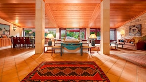 Una habitación amplia con techo de madera, una cama grande, un área de comedor y vistas al exterior.