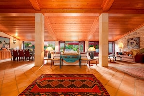 A spacious room with a wooden ceiling, a large bed, a dining area, and a view of the outdoors. - Justininho House - Luxurious Retreat (Ponte de Lima)