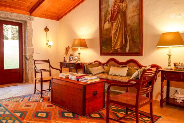 Una habitación acogedora con un banco de madera, un baúl rojo y un cuadro en la pared.