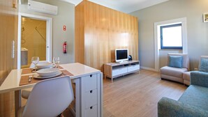 A modern living room with a flat-screen TV, a sofa, and a dining area with a table set for two. - Casa S. Vicente- with private parking (Viana do Castelo)