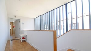 A modern interior with a wooden floor, white walls, and a glass partition. - Casa S. Vicente- with private parking (Viana do Castelo)