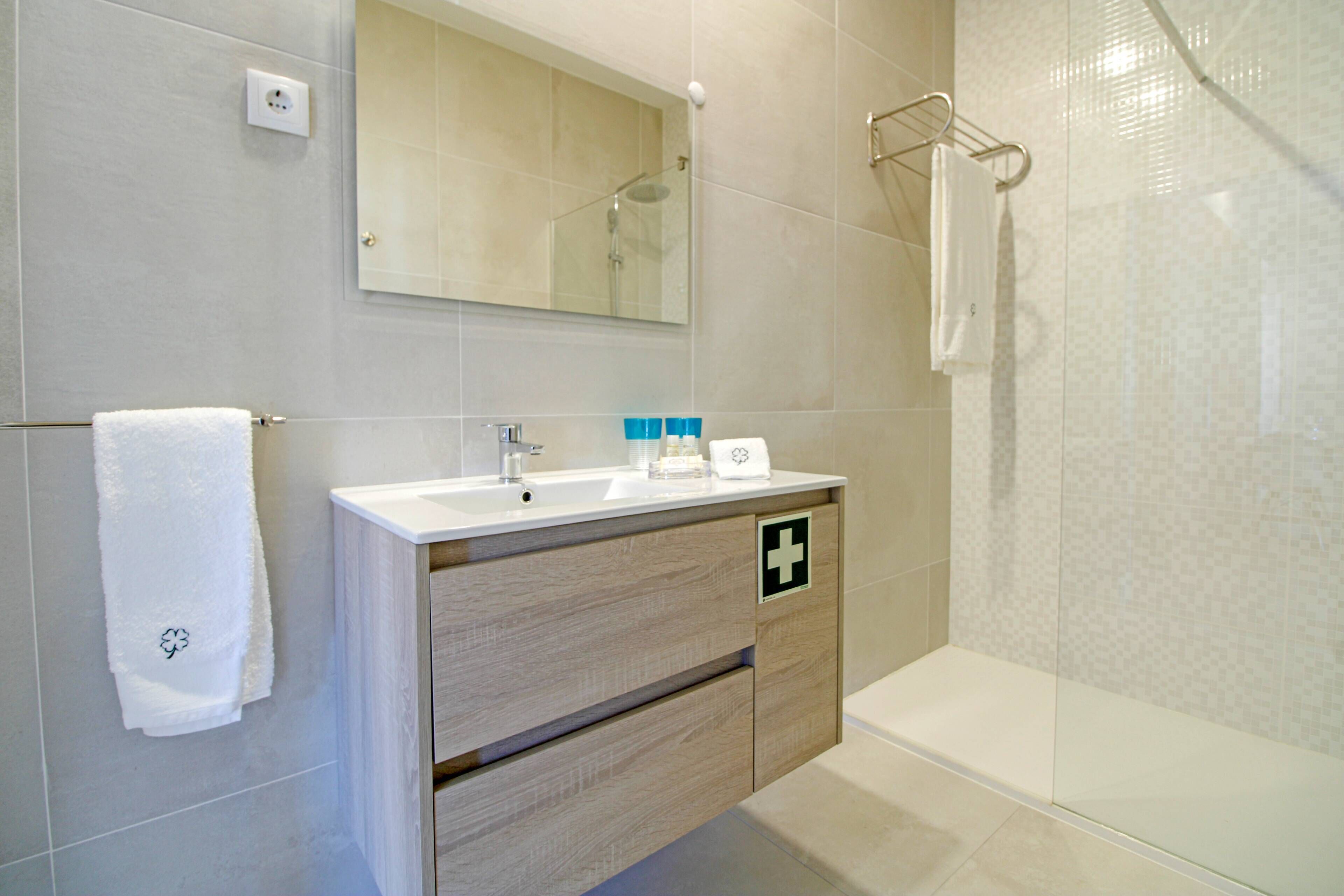 Un baño moderno con lavamanos, espejo y ducha.