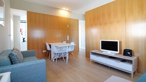 A modern living room with a wooden wall, a white TV stand, and a dining area with a white table and chairs. - Casa S. Vicente- with private parking (Viana do Castelo)