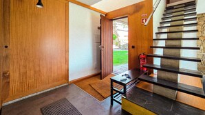 Un intérieur moderne avec une porte en bois, un escalier agrémenté d’éléments en pierre et un extincteur fixé au mur.