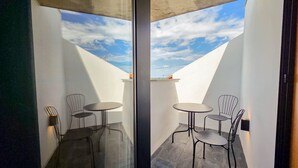 Une pièce moderne avec une cloison en verre, deux petites tables rondes et des chaises en métal.