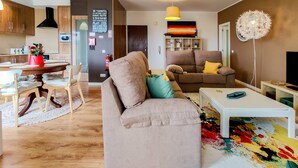 A modern living room with a sofa, a coffee table, and a TV stand. There is a dining area with a table and chairs. - Da Silva House - Ap in Afife with Balcony & SeaView (Viana do Castelo)