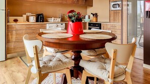 A modern kitchen with wooden cabinets, a central island with chairs, and a red vase with flowers. - Da Silva House - Ap in Afife with Balcony & SeaView (Viana do Castelo)