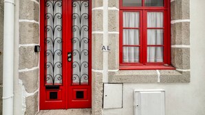 A red door with a metal gate and a window with red shutters.