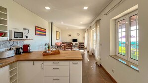 Una cocina moderna con armarios blancos, encimera de madera y un comedor con mesa y sillas.