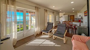 Amplia sala de estar con ventanas grandes, comedor y cocina.