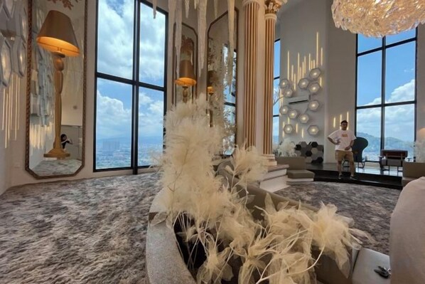 Una habitación amplia con ventanas grandes, una planta decorativa y un candelabro.