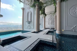Piscina infinita en la azotea con vistas a la ciudad, rodeada de columnas y paneles decorativos.